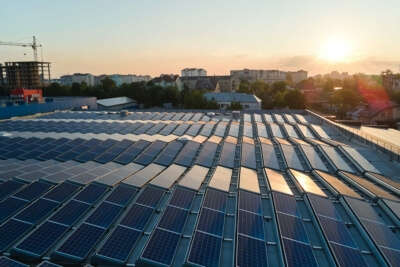 Solarzellen auf einem Dach in einer Stadt bei Sonnenaufgang, symbolisierend den Photovoltaik-Zubau in Baden-Württemberg im ersten Halbjahr 2024